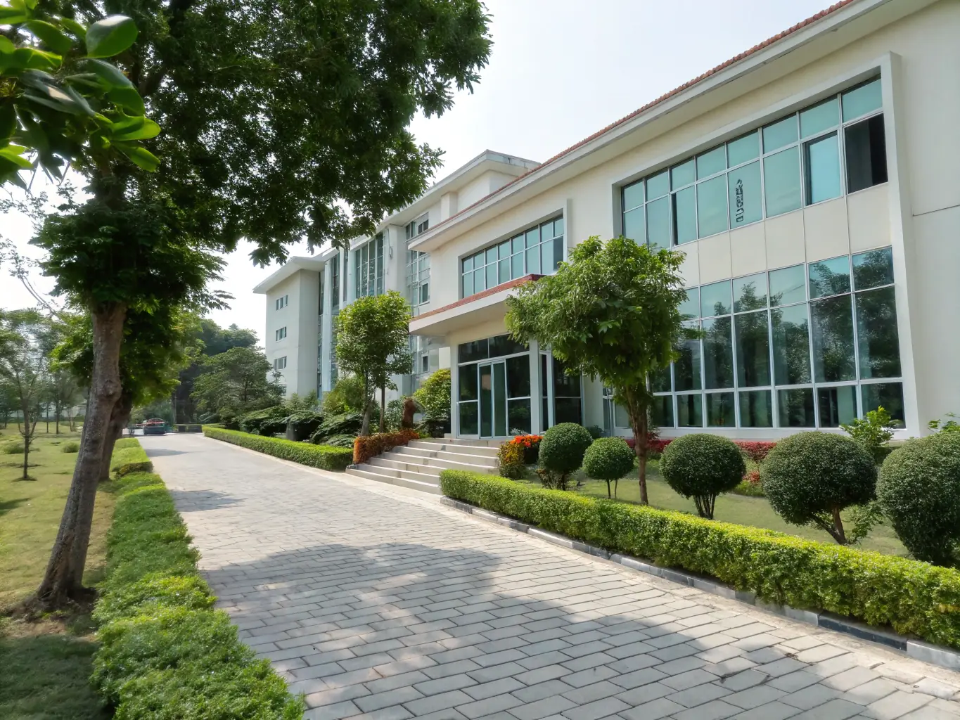 A modern and well-maintained hostel building at Chinhoyi High School, showing students entering and exiting, with lush green lawns and trees in the background.